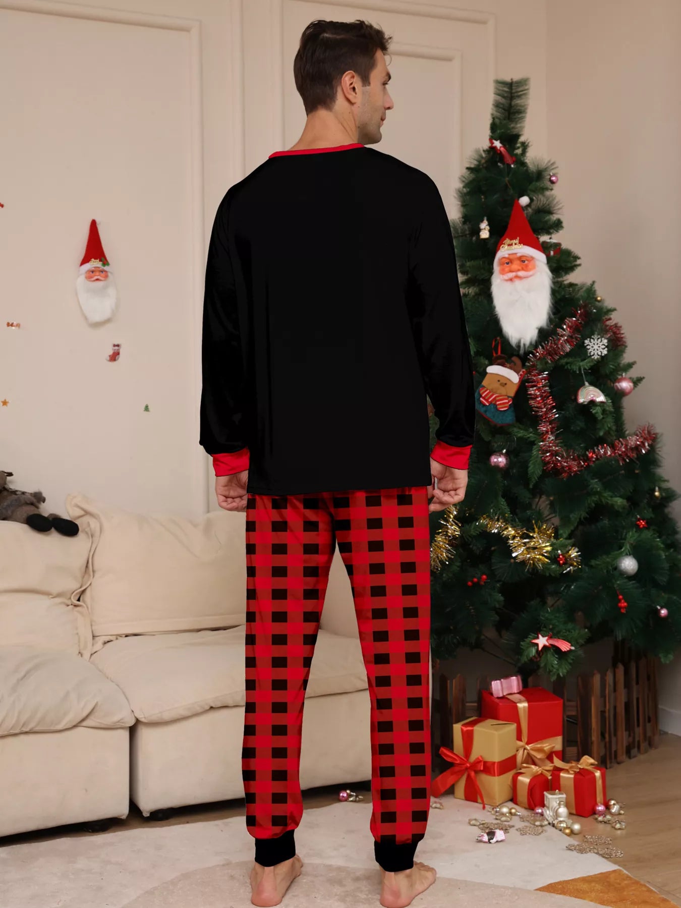 Dad modeling matching Christmas Crew pajama sets with festive black graphic tops and red and black plaid pants.