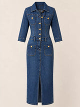 Woman wearing a dark blue button-front denim midi dress with gold-tone buttons, collared neckline, patch pockets, contrast stitching and front slit.