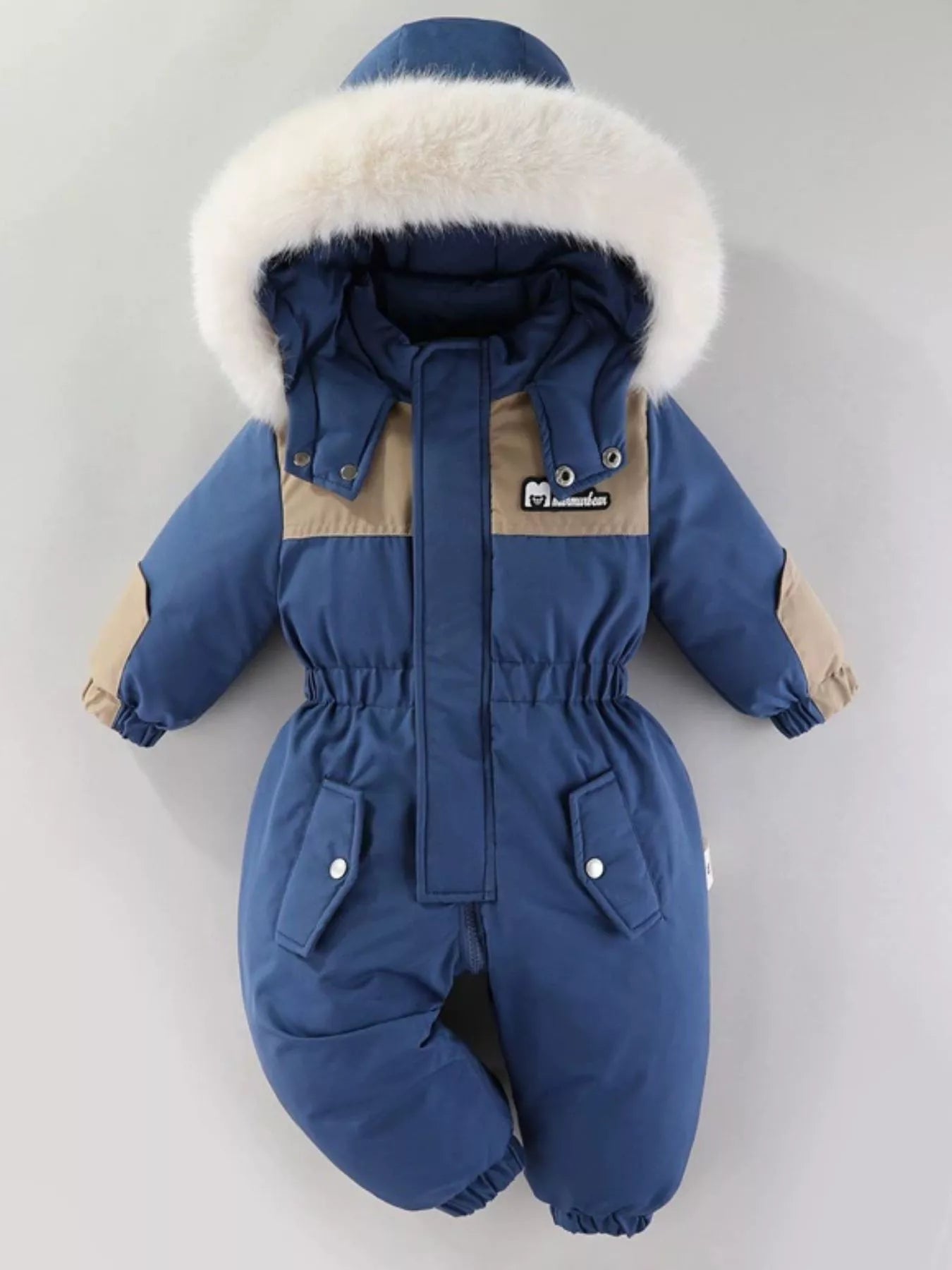 Children's dark blue one-piece winter snowsuit featuring a fluffy white faux fur-trimmed hood, rust-colored accents, elasticized waist, and front pockets.