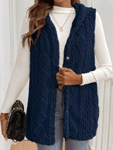 Woman wearing a dark blue hooded sherpa vest coat over a white long-sleeve top with blue jeans for a cozy fall and winter outfit.