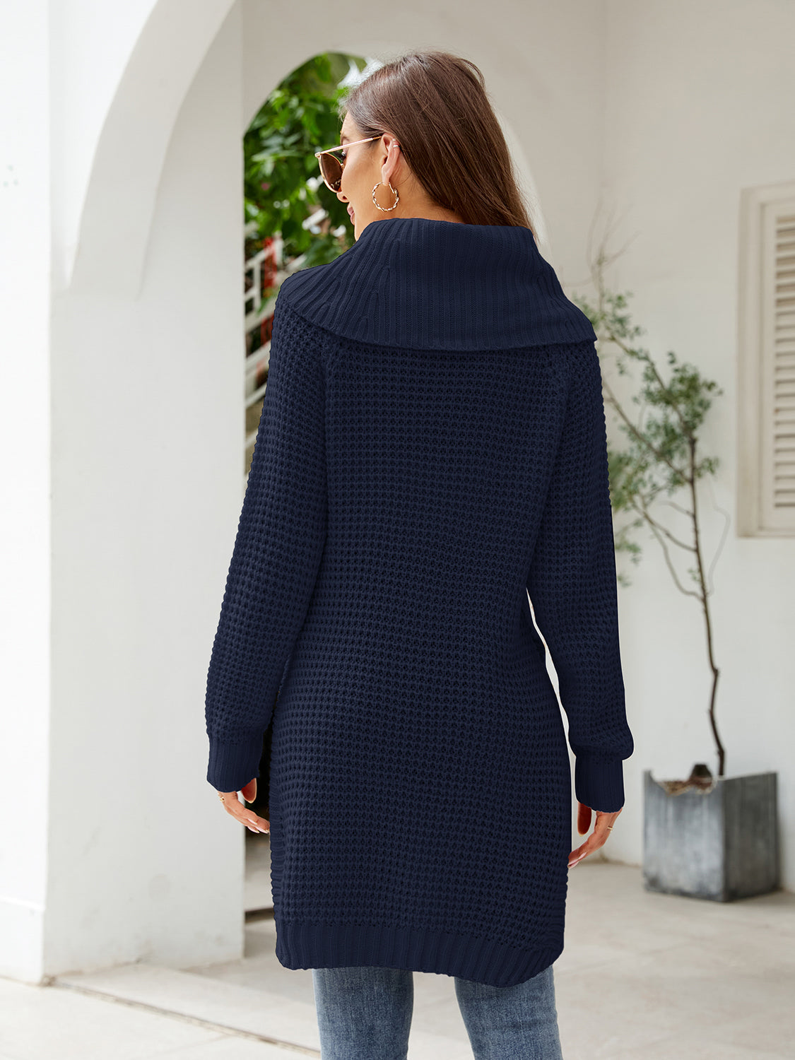 Woman wearing a dark blue turtleneck waffle-knit slit sweater dress with long sleeves and a relaxed fit for fall.
