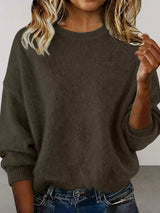 Woman wearing a dark brown round neck dropped shoulder sweater with dark-wash jeans.