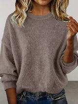 Woman wearing a dark gray round neck dropped shoulder sweater with dark-wash jeans.