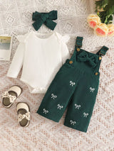 Baby girl three-piece outfit featuring a cream ribbed long-sleeve bodysuit with ruffled shoulders, dark green bow-embroidered overalls and matching green bow headband.