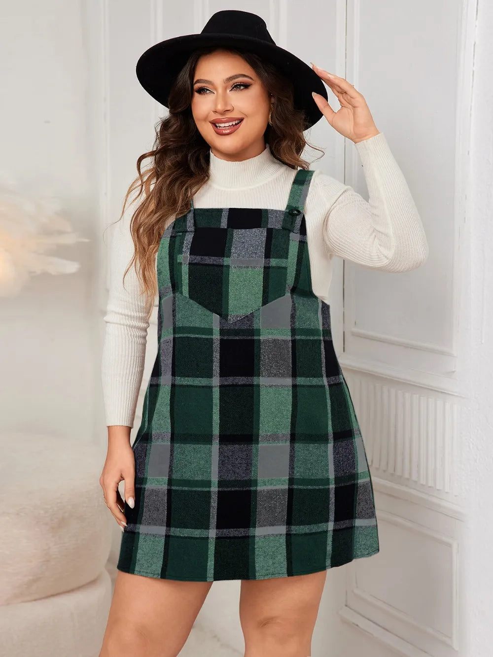 Woman wearing the Honey Plus Size Plaid Wide Strap Overall Dress layered over a cream mock neck sweater with a black felt hat, stylish plus size plaid fall dress from Chic Mystik Boutique.