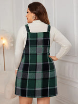 Woman wearing the Honey Plus Size Plaid Wide Strap Overall Dress layered over a cream mock neck sweater with a black felt hat, stylish plus size plaid fall dress from Chic Mystik Boutique.