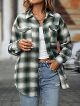 Woman wearing a deep green plaid oversized button-up shirt layered over a white top with jeans.