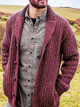 Men's deep rose chunky knit shawl collar cardigan with button-front closure, ribbed texture, and front pockets, layered over a gray button-down shirt.