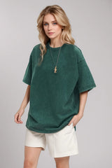 Woman wearing an oversized deep teal Basic Bae round-neck half-sleeve T-shirt styled with dark denim jeans and a long pendant necklace for a relaxed, casual look.