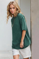 Woman wearing an oversized deep teal Basic Bae round-neck half-sleeve T-shirt styled with dark denim jeans and a long pendant necklace for a relaxed, casual look.