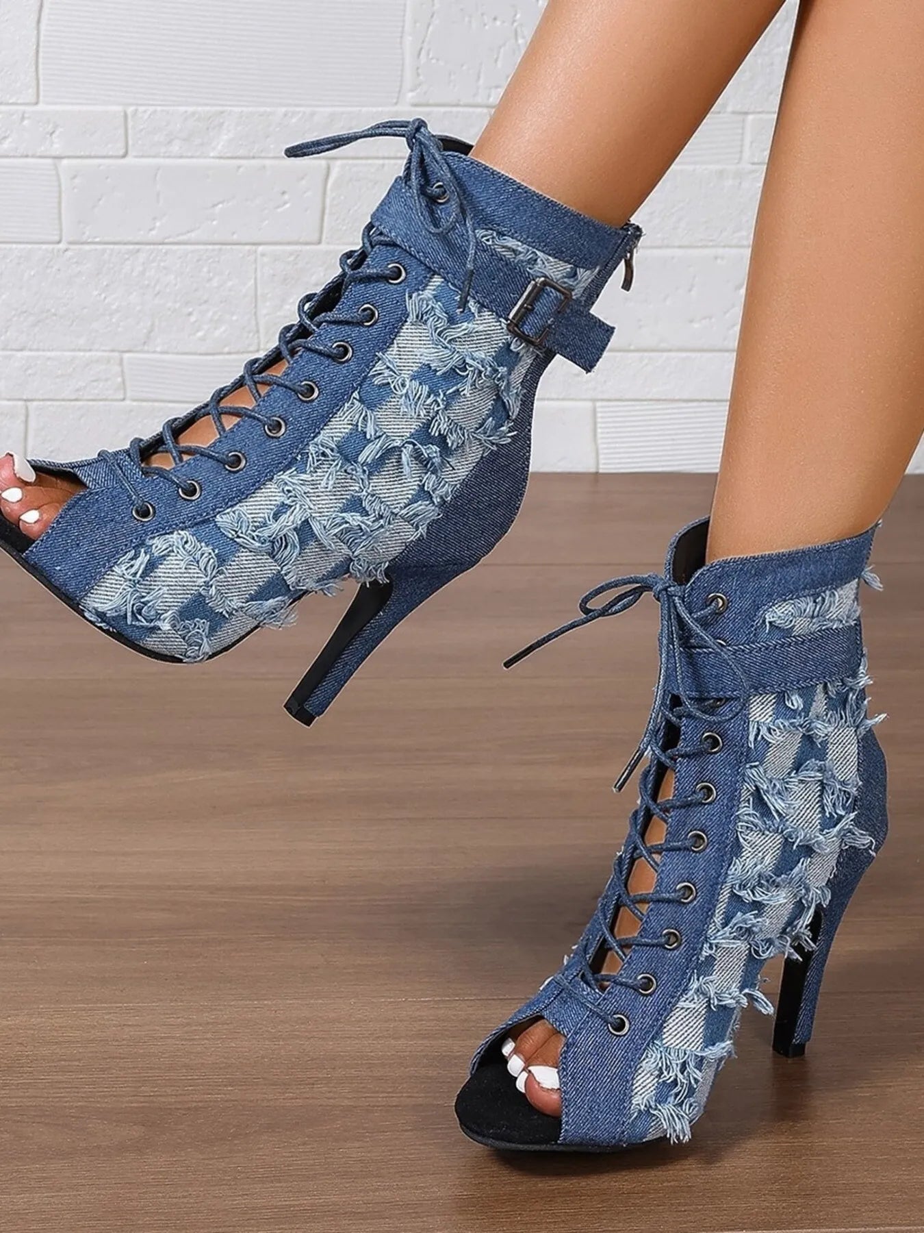 Blue denim lace-up high-heeled shoes with floral patterns on a wooden floor.