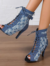 Blue denim lace-up high-heeled shoes with floral patterns on a wooden floor.