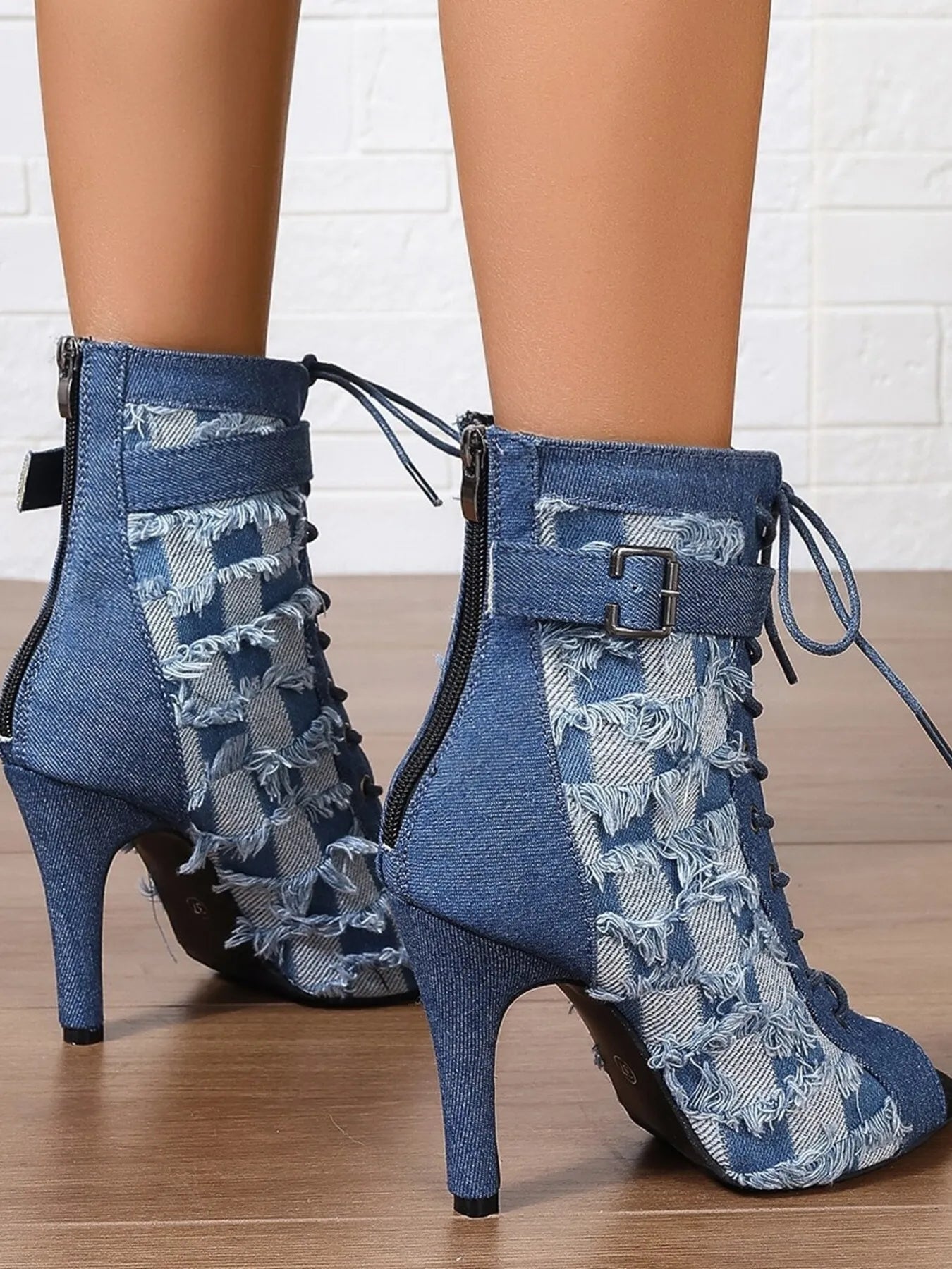Blue denim high-heeled boots with lace details on a wooden floor.