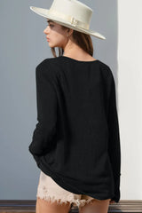 Person wearing a black sweater and white hat against a gray wall