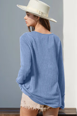 Person wearing a light blue sweater and white hat against a gray wall.