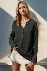 Woman wearing a dark gray textured shirt and white shorts against a light background