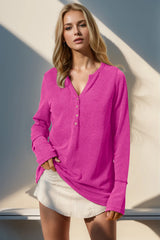 Woman wearing a fuchsia pink sweater and white shorts against a neutral background