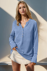 Woman wearing a light blue long-sleeve shirt and white skirt against a neutral background