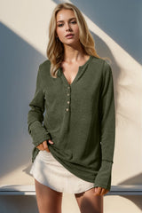Woman wearing a green textured shirt and white shorts against a neutral background
