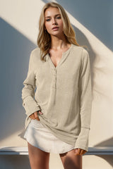 Woman wearing a beige sweater and white skirt against a neutral background