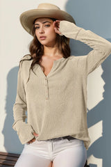 Woman wearing a beige knit sweater and straw hat against a light background