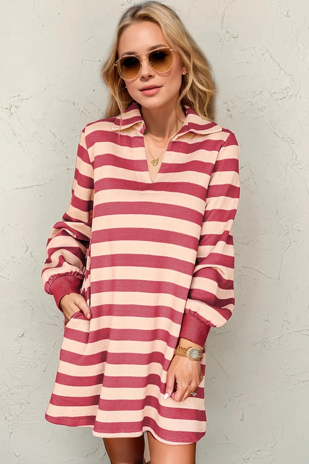 Woman wearing a red and white striped dress against a textured wall.