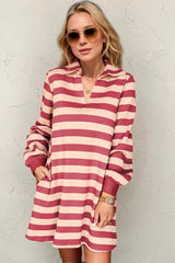 Woman wearing a red and white striped dress against a textured wall.