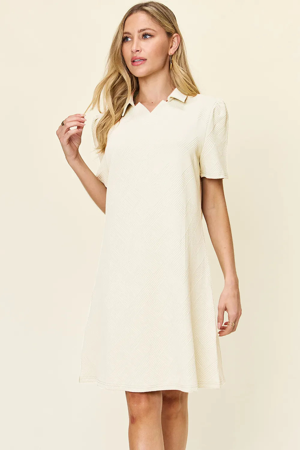 Woman wearing a cream-colored dress against a plain background