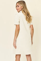 Woman wearing a cream-colored dress against a plain background