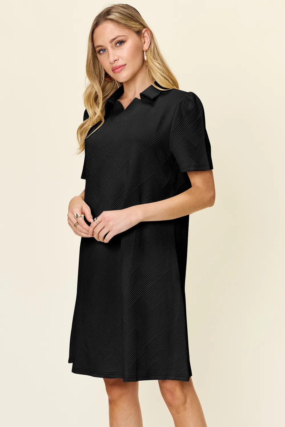 Woman wearing a black dress with short sleeves on a beige background