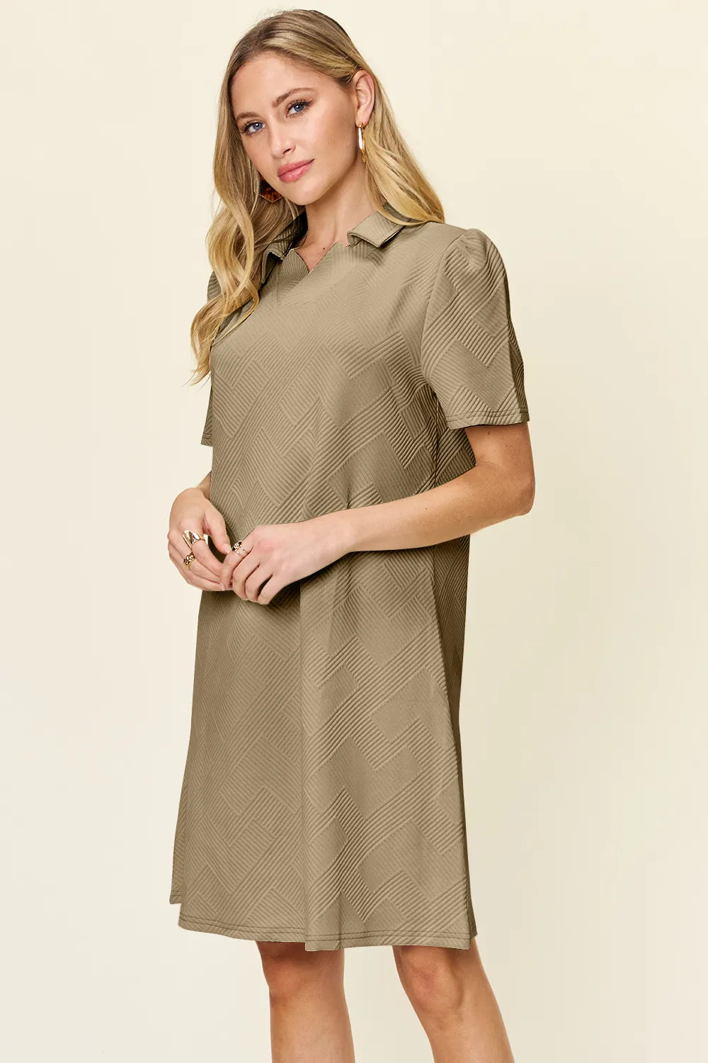 Woman wearing a khaki dress with a polo collar on a beige background