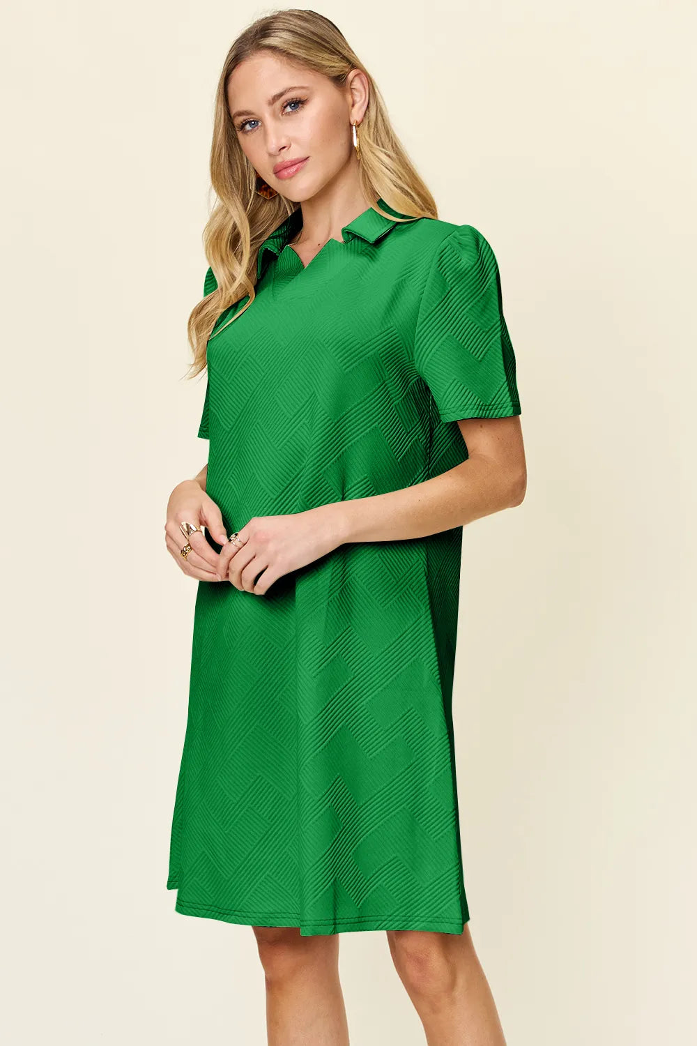 Woman wearing a green dress with a collar on a beige background