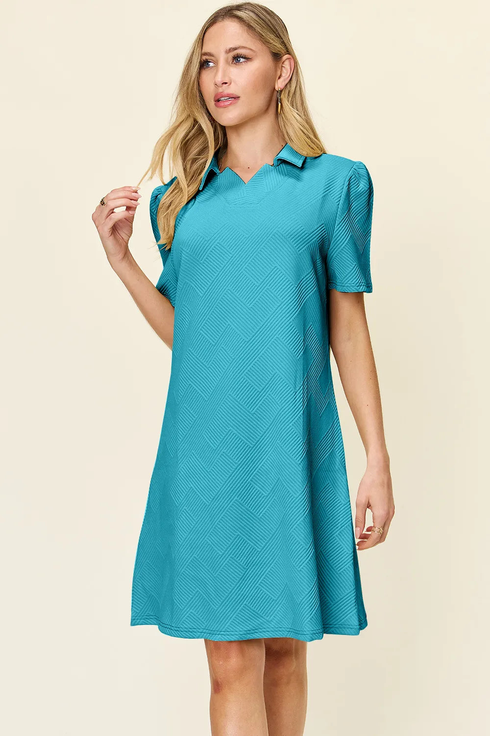 Woman wearing a pastel blue dress with a collar on a beige background