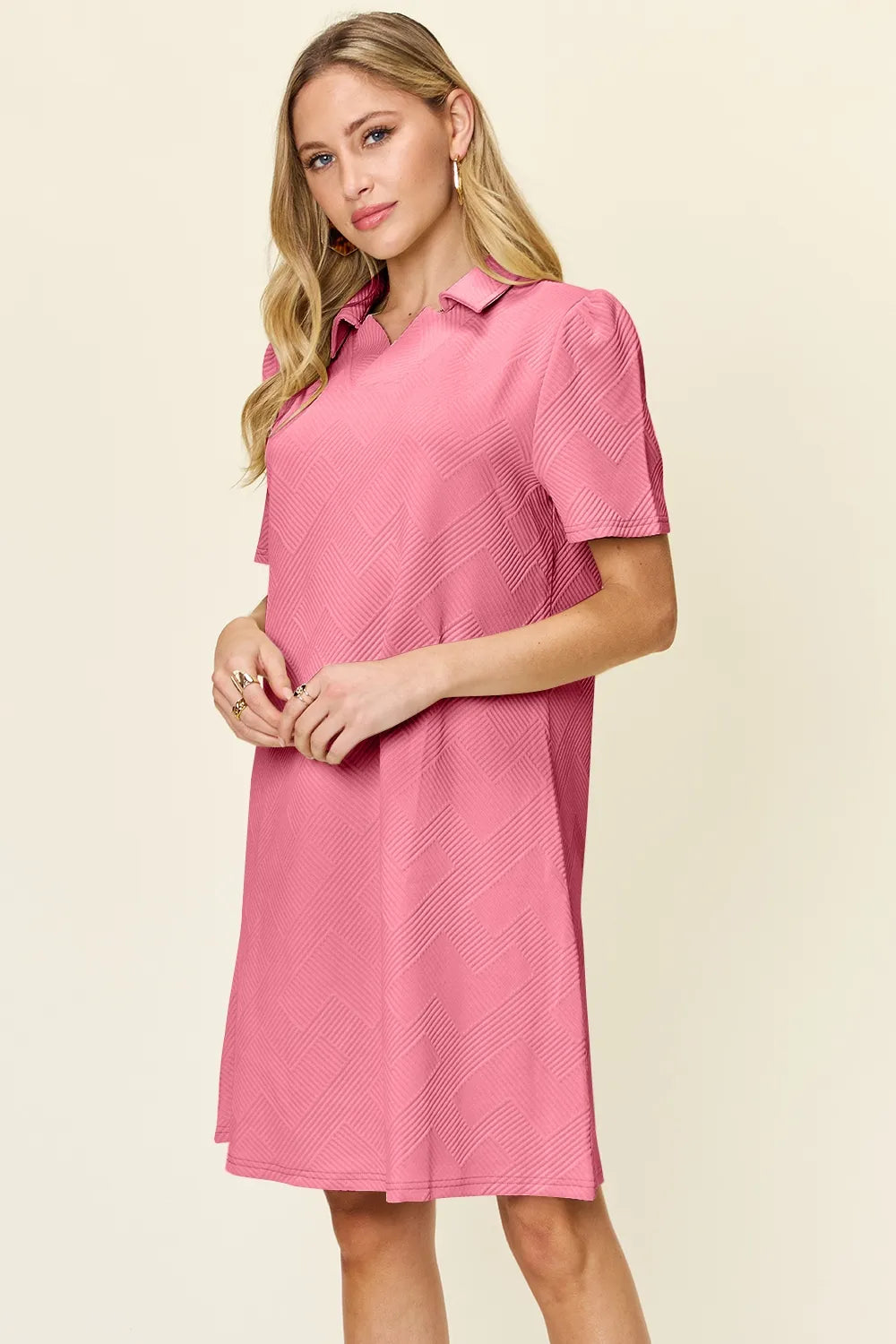 Woman wearing a pink dress with a collar on a beige background