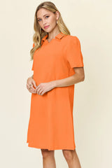 Woman wearing an orange dress with a collar on a beige background