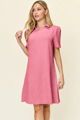 Woman wearing a pink dress with a collar on a beige background