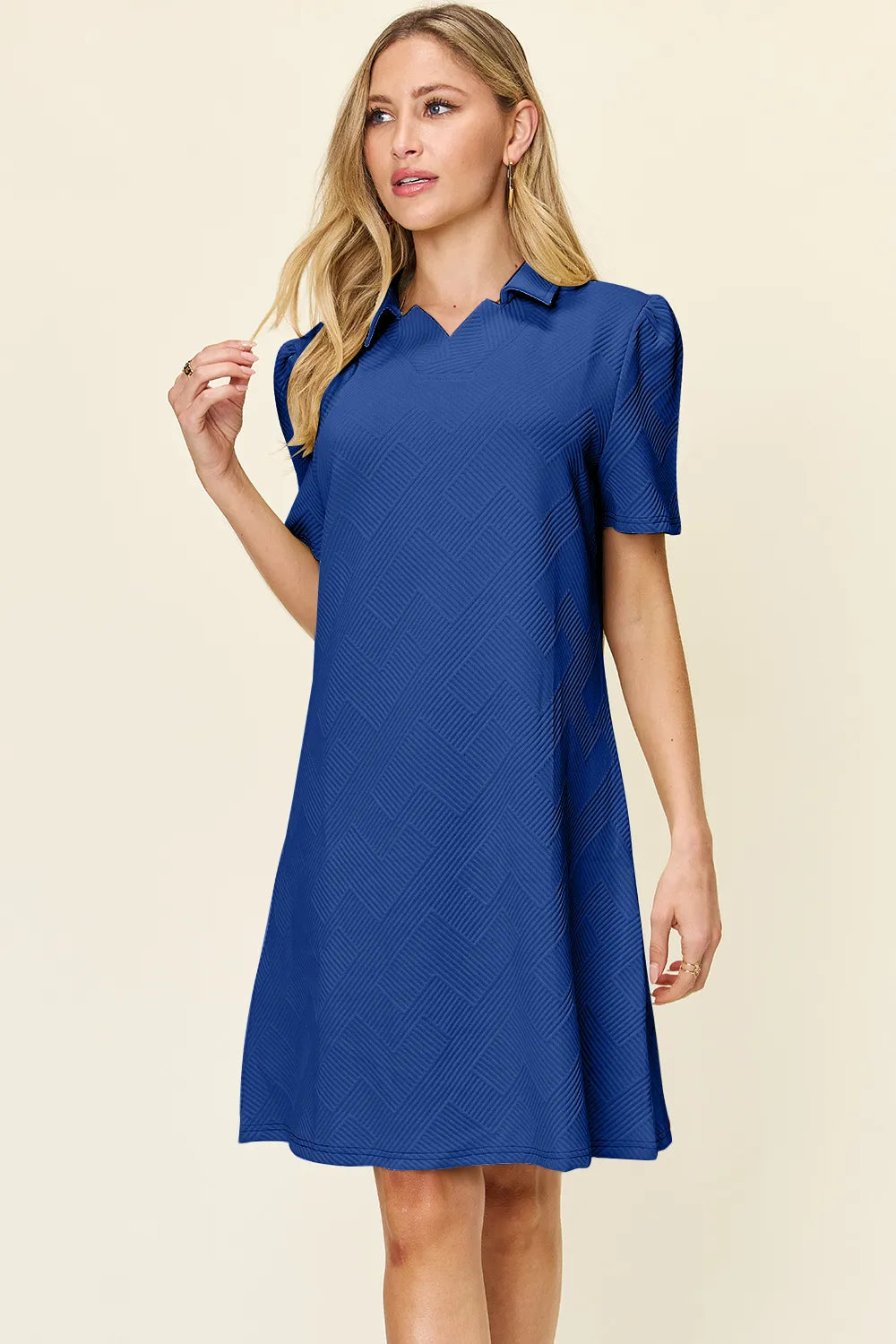 Woman wearing a royal blue dress against a beige background