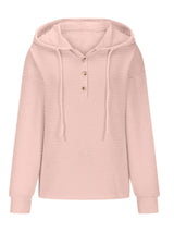Woman wearing a blush pink textured drawstring quarter-button long sleeve hoodie paired with black jeans, perfect for casual fall outfits, available in 10 colors and sizes Small–2XL.