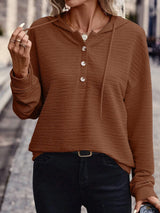 Woman wearing a brown textured drawstring quarter-button long sleeve hoodie paired with black jeans, perfect for casual fall outfits, available in 10 colors and sizes Small–2XL.