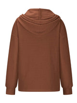 Woman wearing a brown textured drawstring quarter-button long sleeve hoodie paired with black jeans, perfect for casual fall outfits, available in 10 colors and sizes Small–2XL.