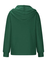 Woman wearing a dark green textured drawstring quarter-button long sleeve hoodie paired with black jeans, perfect for casual fall outfits, available in 10 colors and sizes Small–2XL.