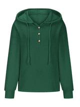 Woman wearing a dark green textured drawstring quarter-button long sleeve hoodie paired with black jeans, perfect for casual fall outfits, available in 10 colors and sizes Small–2XL.