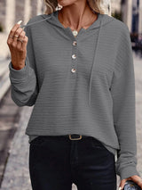 Woman wearing a gray textured drawstring quarter-button long sleeve hoodie paired with black jeans, perfect for casual fall outfits, available in 10 colors and sizes Small–2XL.