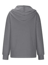 Woman wearing a gray textured drawstring quarter-button long sleeve hoodie paired with black jeans, perfect for casual fall outfits, available in 10 colors and sizes Small–2XL.