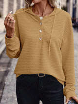 Woman wearing a mustard textured drawstring quarter-button long sleeve hoodie paired with black jeans, perfect for casual fall outfits, available in 10 colors and sizes Small–2XL.