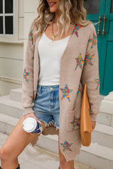 Woman wearing a dust storm open-front cardigan with colorful star print, front pockets, denim shorts and black Western boots.