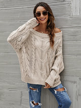 Woman wearing a dust storm cable knit openwork off-shoulder sweater with distressed jeans and a wide-brim hat.