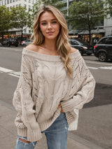 Woman wearing a dust storm cable knit openwork off-shoulder sweater with distressed jeans and a wide-brim hat.
