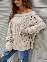 Woman wearing a dust storm cable knit openwork off-shoulder sweater with distressed jeans and a wide-brim hat.