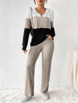 Woman wearing a dust storm, black and white color block half zip hooded top with matching ribbed-look pants.